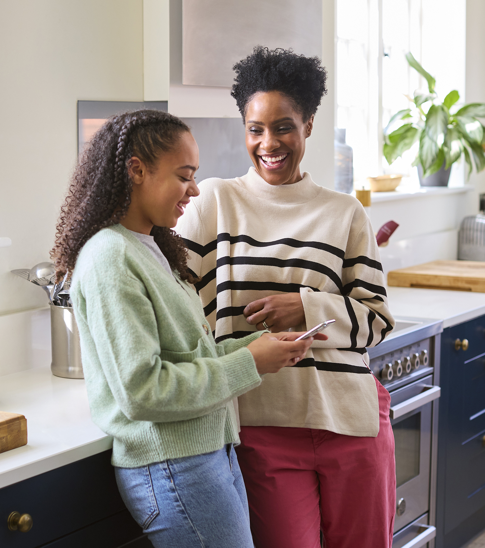 Mother Talking With Teenage Daughter At Home As She Checks Social Media On Mobile Phone